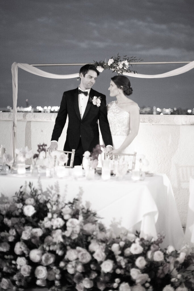 bride and groom standing at sweethearts table at riverside hotel wedding